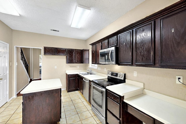 1523 Allen Dr, Cedar Hill, TX 75104 - kitchen featuring stainless steel appliances, a kitchen island, light tile patterned floors, a textured ceiling, and light countertops