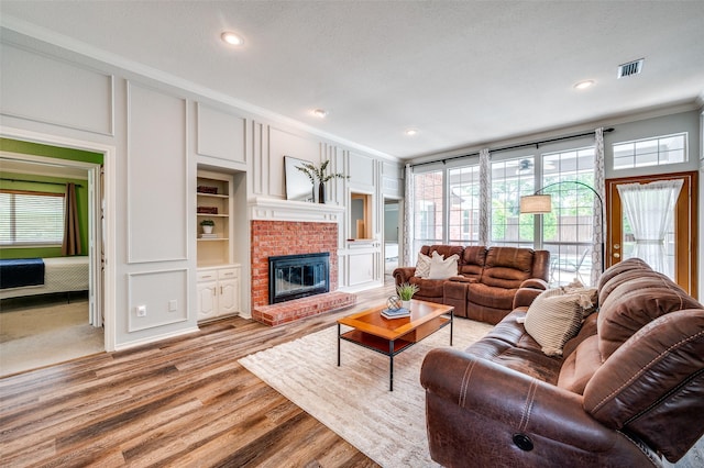 3336 Sage Brush Trl, Plano, TX 75023 - living room featuring a decorative wall, crown molding, a brick fireplace, light wood-style flooring, and recessed lighting