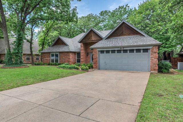 ranch-style house featuring a shingled roof, a front yard, driveway, brick siding, and an attached garage