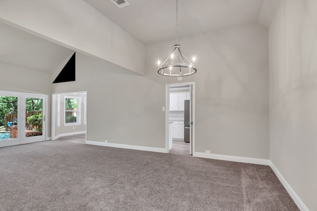 carpeted empty room featuring high vaulted ceiling, a chandelier, and baseboards