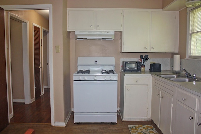 205 N Texas St, Whitney, TX 76692 - kitchen with white range with gas stovetop, under cabinet range hood, a sink, dark wood-style floors, and white cabinets