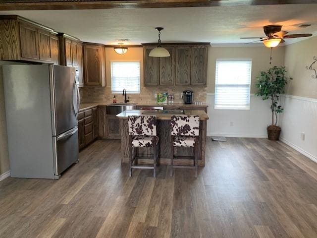 222 County Road 2195, Decatur, TX 76234 - kitchen with freestanding refrigerator, a breakfast bar area, wood finished floors, a center island, and a ceiling fan