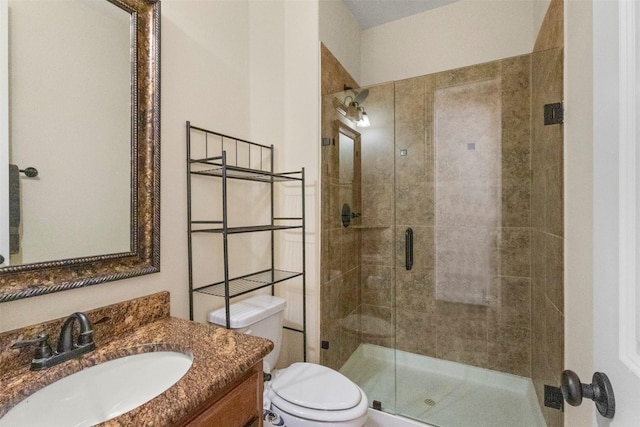 bathroom with a shower stall, toilet, and vanity