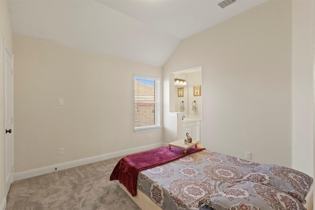 carpeted bedroom featuring lofted ceiling, baseboards, ensuite bathroom, and a sink