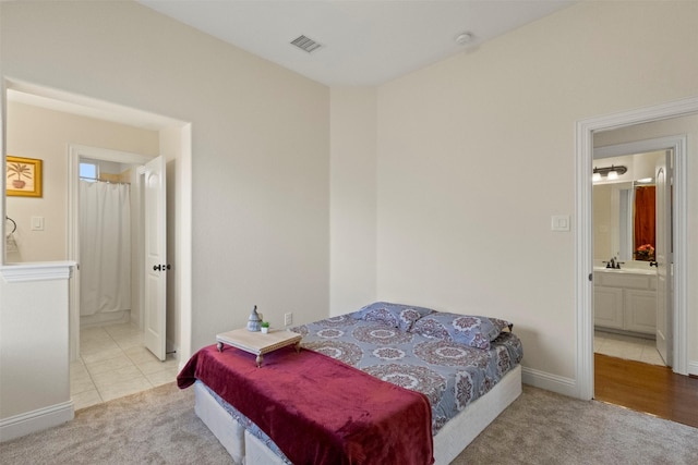 bedroom featuring carpet flooring, ensuite bathroom, baseboards, and a sink