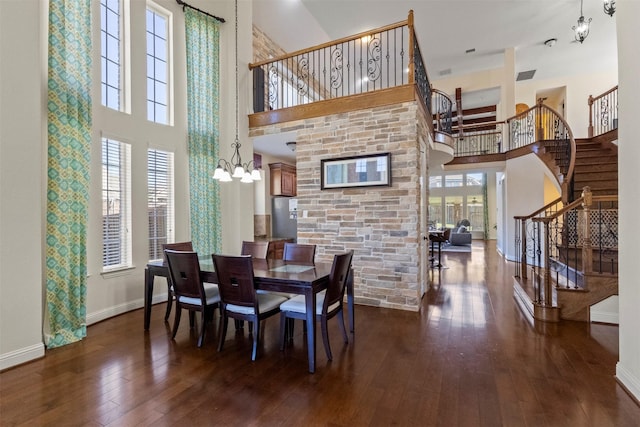 dining room featuring a high ceiling, a chandelier, stairs, dark wood-style flooring, and baseboards