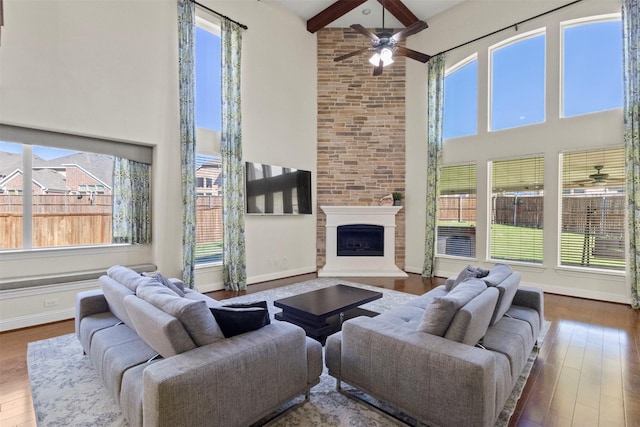 living room with a towering ceiling, a ceiling fan, wood-type flooring, plenty of natural light, and a fireplace