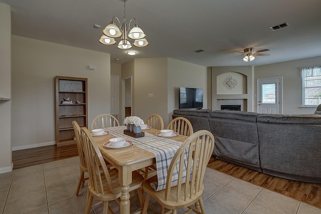 1300 Shelby Ct, Wylie, TX 75098 - dining room with light tile patterned floors, a chandelier, a fireplace, and ceiling fan