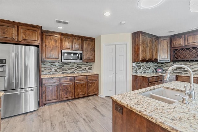 1717 Adams Ln, Azle, TX 76020 - kitchen with stainless steel appliances, a sink, tasteful backsplash, light stone countertops, and light wood-style flooring