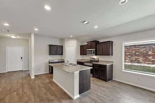 4612 Corktree Ln, Fort Worth, TX 76036 - kitchen featuring appliances with stainless steel finishes, a sink, light wood finished floors, baseboards, and a center island with sink
