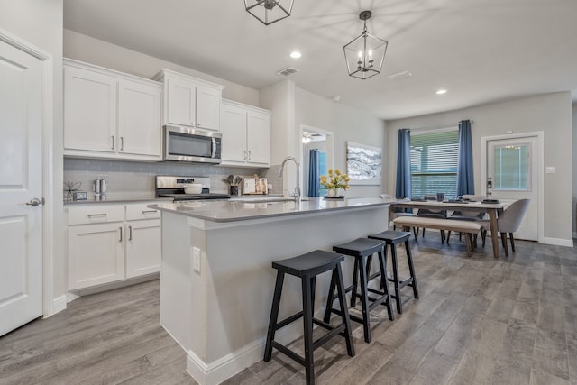 15720 Redgrave Dr, Fort Worth, TX 76247 - kitchen featuring stainless steel appliances, light wood-style floors, a kitchen island with sink, backsplash, and a sink