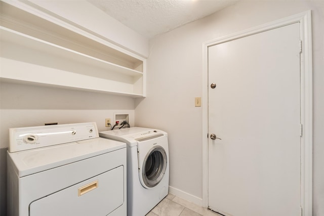 washroom with washing machine and clothes dryer, a textured ceiling, and baseboards