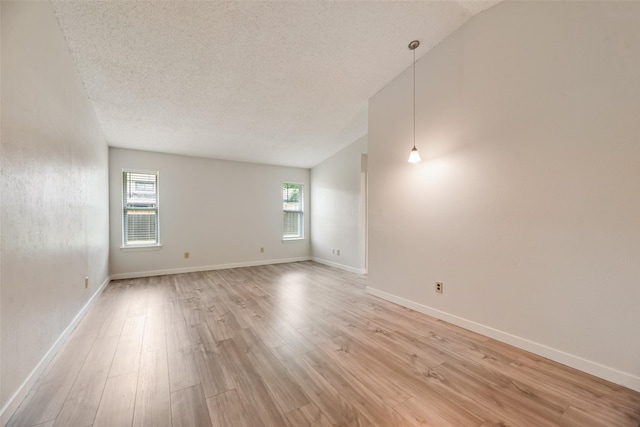 unfurnished room with light wood-type flooring, a textured ceiling, and baseboards
