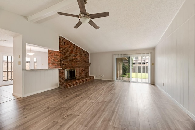 unfurnished living room with wood finished floors, healthy amount of natural light, a ceiling fan, a fireplace, and a textured ceiling