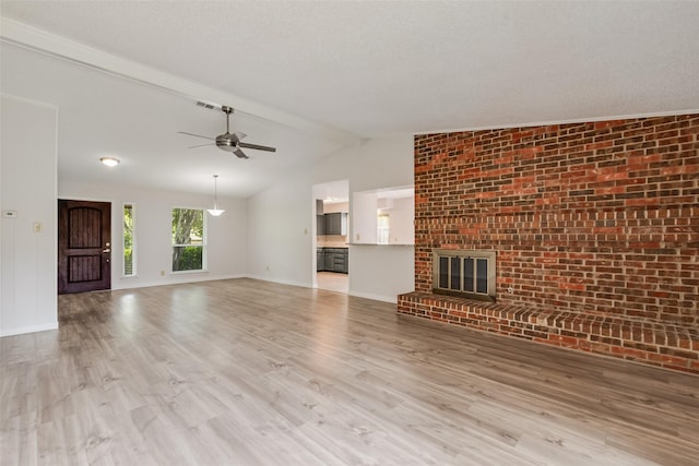 unfurnished living room with wood finished floors, ceiling fan, brick wall, baseboards, and a fireplace