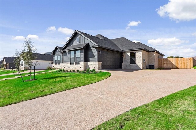 10201 Castleberry Ln, Waco, TX 76712 - view of front facade featuring concrete driveway, an attached garage, board and batten siding, central AC, and stone siding