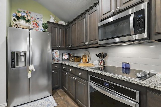 1440 Glade Meadows Dr, Burleson, TX 76058 - kitchen featuring stainless steel appliances, backsplash, lofted ceiling, dark brown cabinetry, and dark wood-style flooring