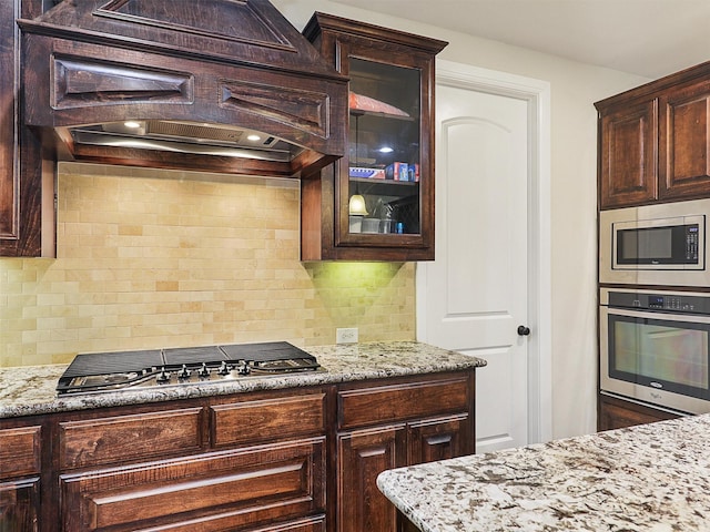 2165 Hidalgo Ln, Frisco, TX 75034 - kitchen with appliances with stainless steel finishes, glass insert cabinets, tasteful backsplash, and light stone countertops