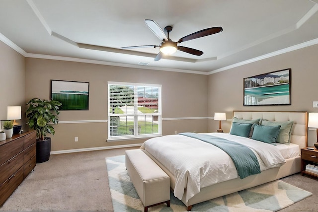 carpeted bedroom with a raised ceiling, ornamental molding, ceiling fan, and baseboards
