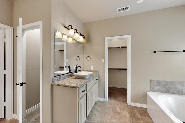 full bath featuring a walk in closet, baseboards, a garden tub, and vanity