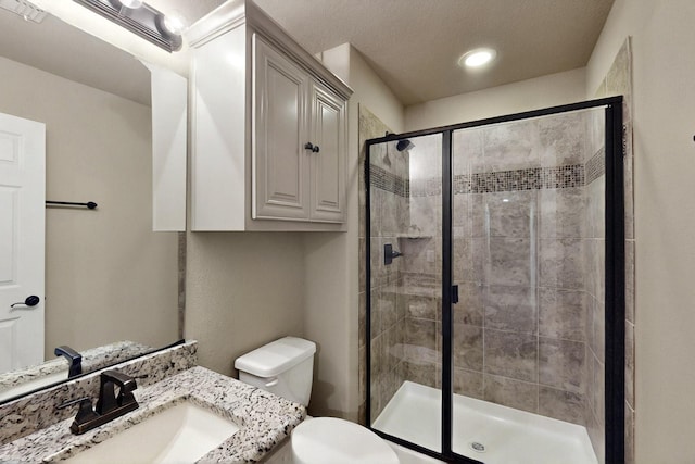 bathroom featuring a shower stall, toilet, vanity, and recessed lighting