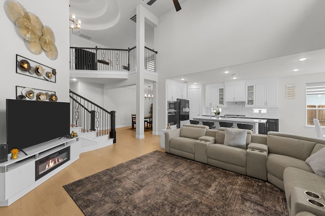 10969 Coastal Violet Rd, Frisco, TX 75035 - living room featuring wood finished floors, stairway, ceiling fan, a high ceiling, and a glass covered fireplace