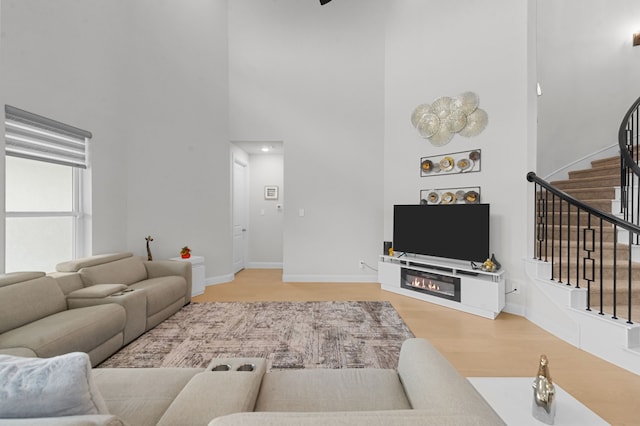 10969 Coastal Violet Rd, Frisco, TX 75035 - living area with a high ceiling, stairway, wood finished floors, baseboards, and a glass covered fireplace