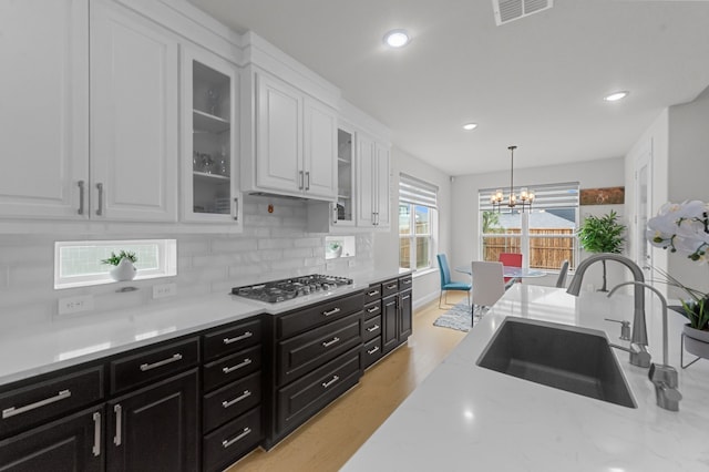 10969 Coastal Violet Rd, Frisco, TX 75035 - kitchen featuring a sink, stainless steel gas cooktop, dark cabinetry, white cabinets, and a chandelier