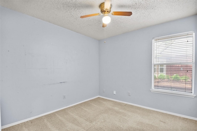 carpeted empty room featuring healthy amount of natural light, a textured ceiling, a ceiling fan, and baseboards