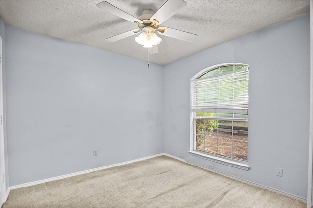 spare room featuring a textured ceiling, carpet, a ceiling fan, and baseboards