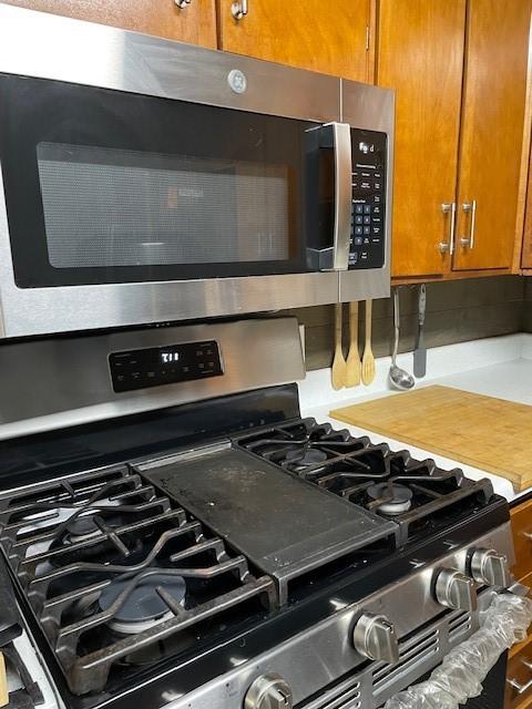 kitchen view of appliances with stainless steel finishes, brown cabinetry, and backsplash