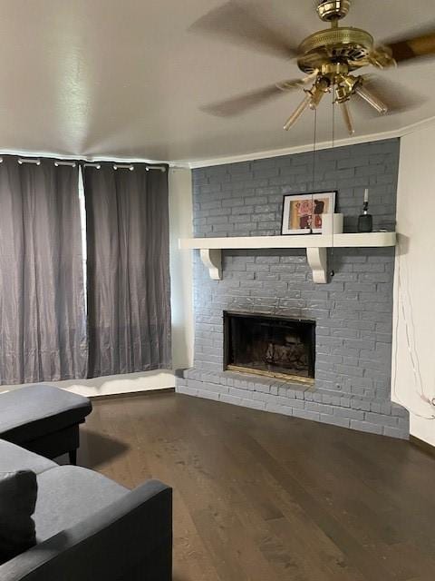living area featuring a ceiling fan, a fireplace, wood finished floors, and crown molding