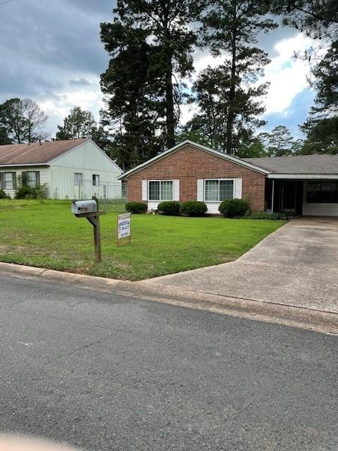 view of front of property featuring a front lawn, concrete driveway, and brick siding