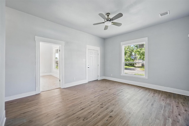 unfurnished room with wood finished floors, a ceiling fan, and baseboards