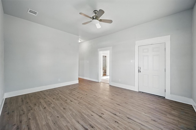 spare room with wood finished floors, a ceiling fan, and baseboards