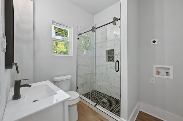 bathroom featuring a sink, wood finished floors, a marble finish shower, toilet, and baseboards