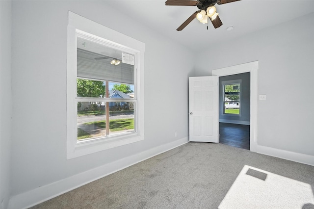 carpeted empty room featuring plenty of natural light, baseboards, and a ceiling fan