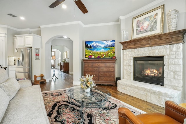 517 Hearth Ter, Argyle, TX 76226 - living room with wood finished floors, ornamental molding, a ceiling fan, arched walkways, and a stone fireplace