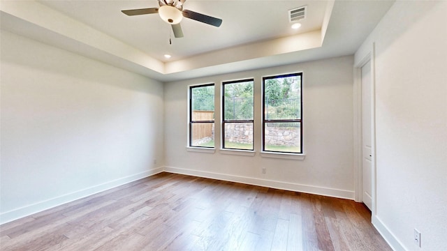 empty room with a tray ceiling, dark wood-style floors, a ceiling fan, baseboards, and recessed lighting