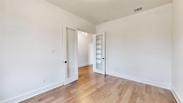 empty room featuring light wood-style floors, french doors, and baseboards