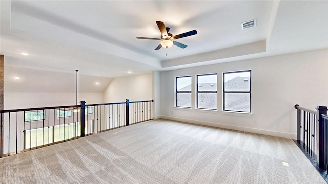 spare room with a ceiling fan, baseboards, light carpet, recessed lighting, and a raised ceiling