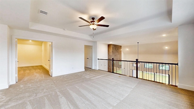 empty room with a ceiling fan, light colored carpet, a tray ceiling, baseboards, and recessed lighting
