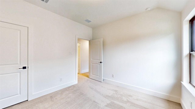 unfurnished bedroom featuring light colored carpet, baseboards, and lofted ceiling