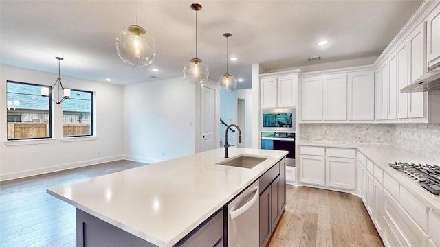 kitchen featuring a sink, appliances with stainless steel finishes, light wood-type flooring, light countertops, and backsplash
