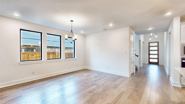 empty room with light wood-style flooring, baseboards, a chandelier, and recessed lighting