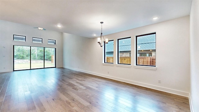 unfurnished room with wood finished floors, baseboards, recessed lighting, and a chandelier