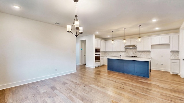 kitchen with stainless steel oven, white cabinetry, light countertops, tasteful backsplash, and recessed lighting