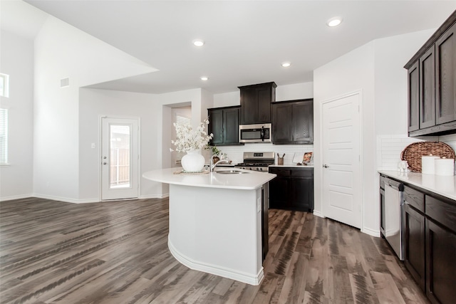 2148 Miramar Dr, Little Elm, TX 75068 - kitchen featuring stainless steel appliances, backsplash, dark wood-type flooring, light countertops, and an island with sink