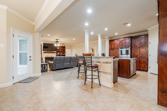 2687 Mcclendon Rd, Weatherford, TX 76088 - kitchen featuring oven, ornamental molding, a kitchen island, a fireplace, and a ceiling fan