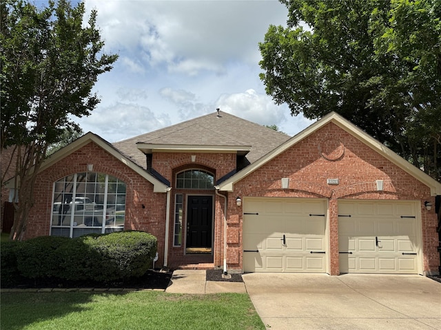 view of front facade with brick siding, an attached garage, driveway, and roof with shingles